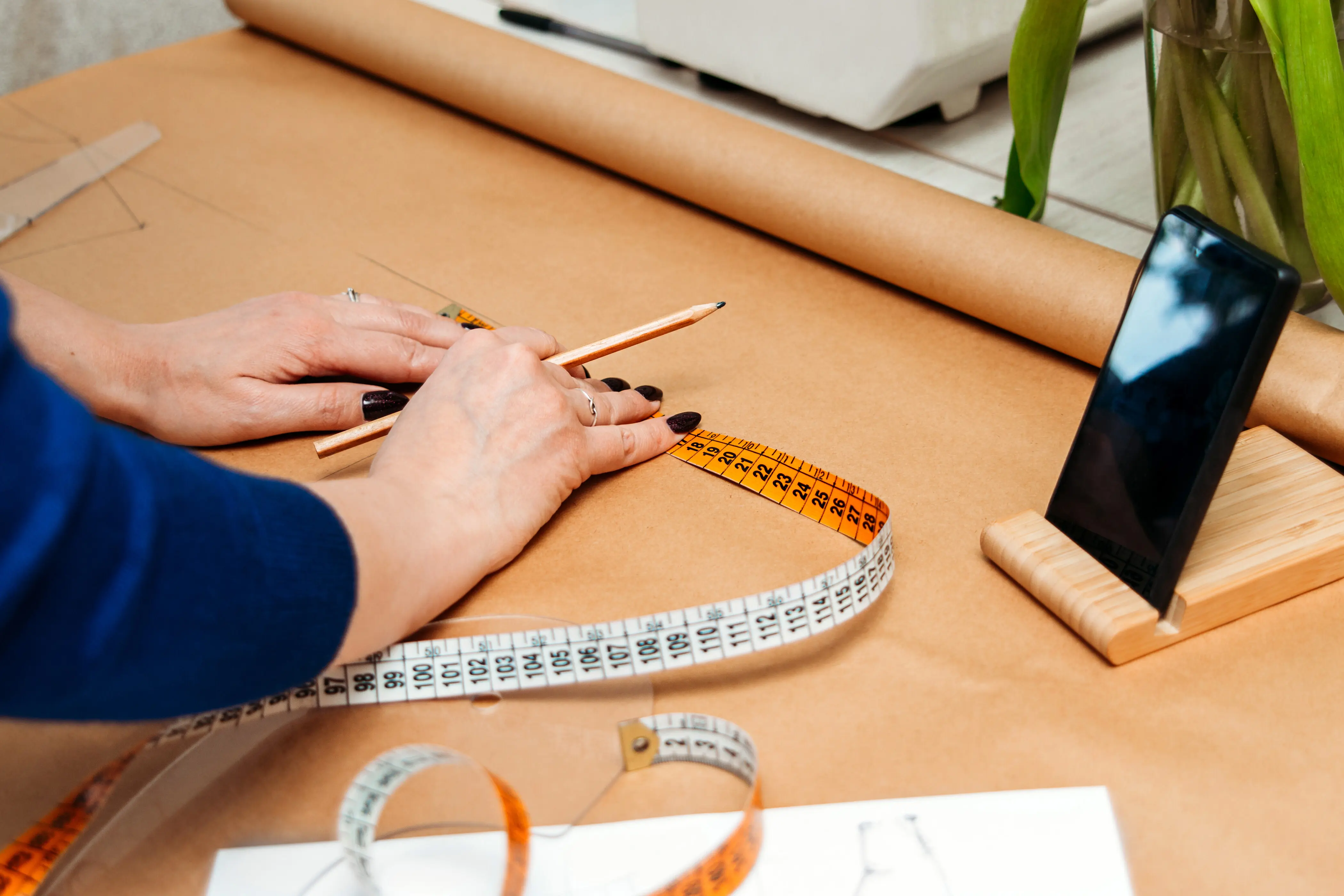 Ein Modedesigner vermisst die Hände einer Frau auf Kraftpapier; Online-Schulung von Bloggern im Zuschneiden.