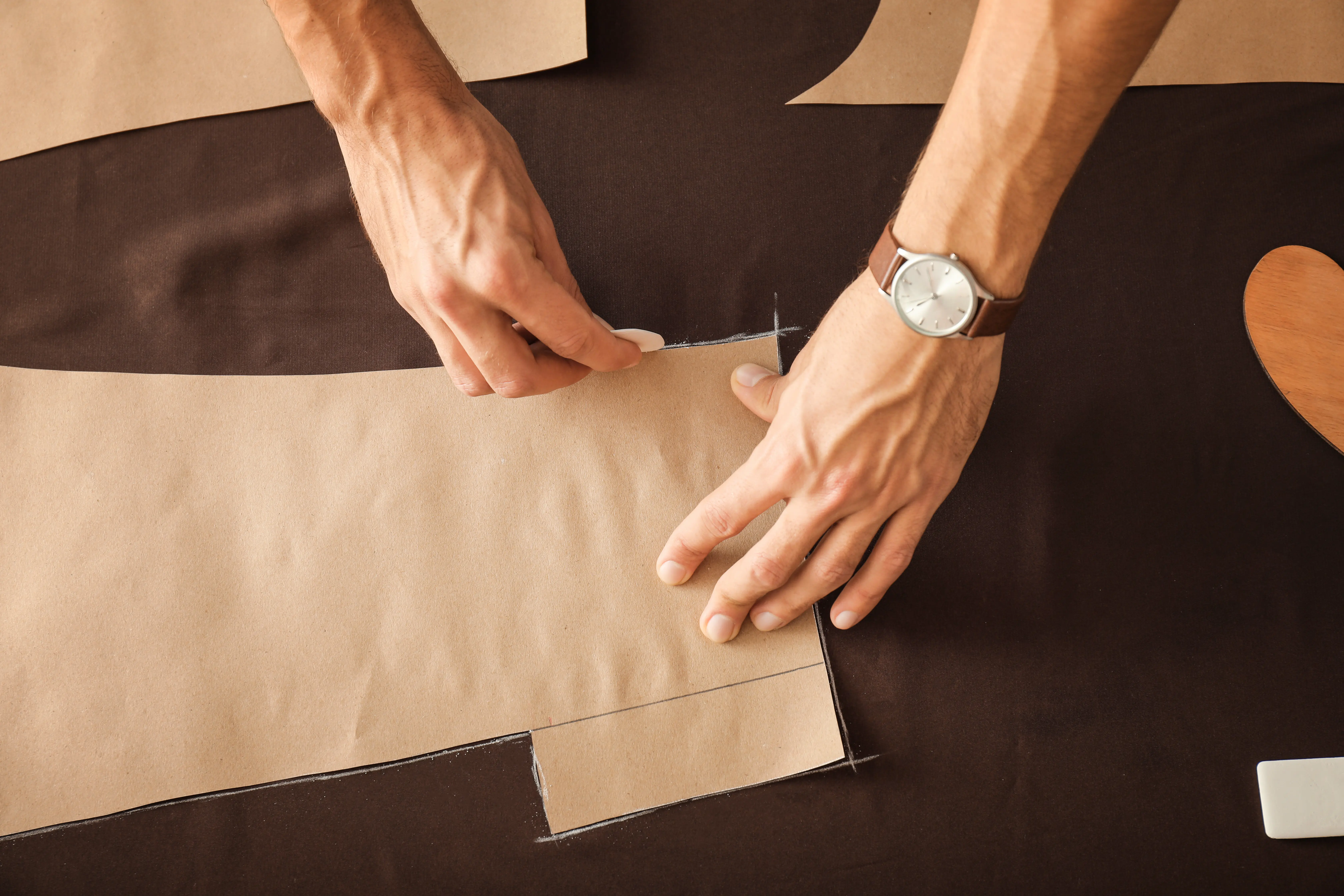 Nahaufnahme eines jungen Schneiders, der mit einem Schnittmuster arbeitet.
